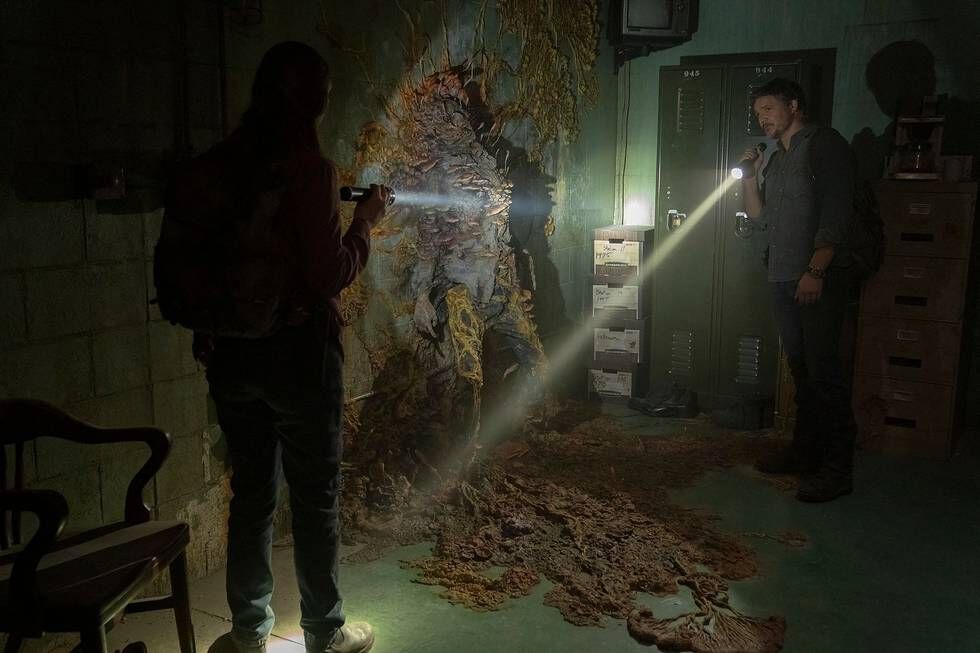 Mann med lommelykt og sopp på veggen. Fra serien The Last of Us.