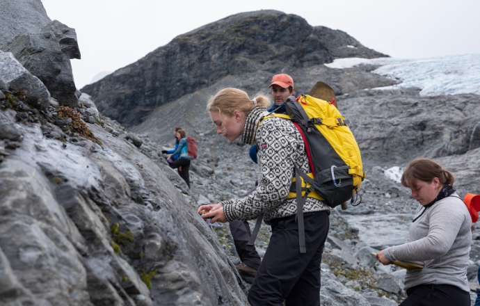 Foto: Studentene i emnet GEO4410 – Glacial and Periglacial Geomorphology, gjør undersøkelser av en bergvegg som har blitt ripet opp av Storbreen. På bakgrunn av observasjoner i felt skriver de rapporter som beskriver og diskuterer landskapets utvikling. Foto: Simen Kjellin/UiO