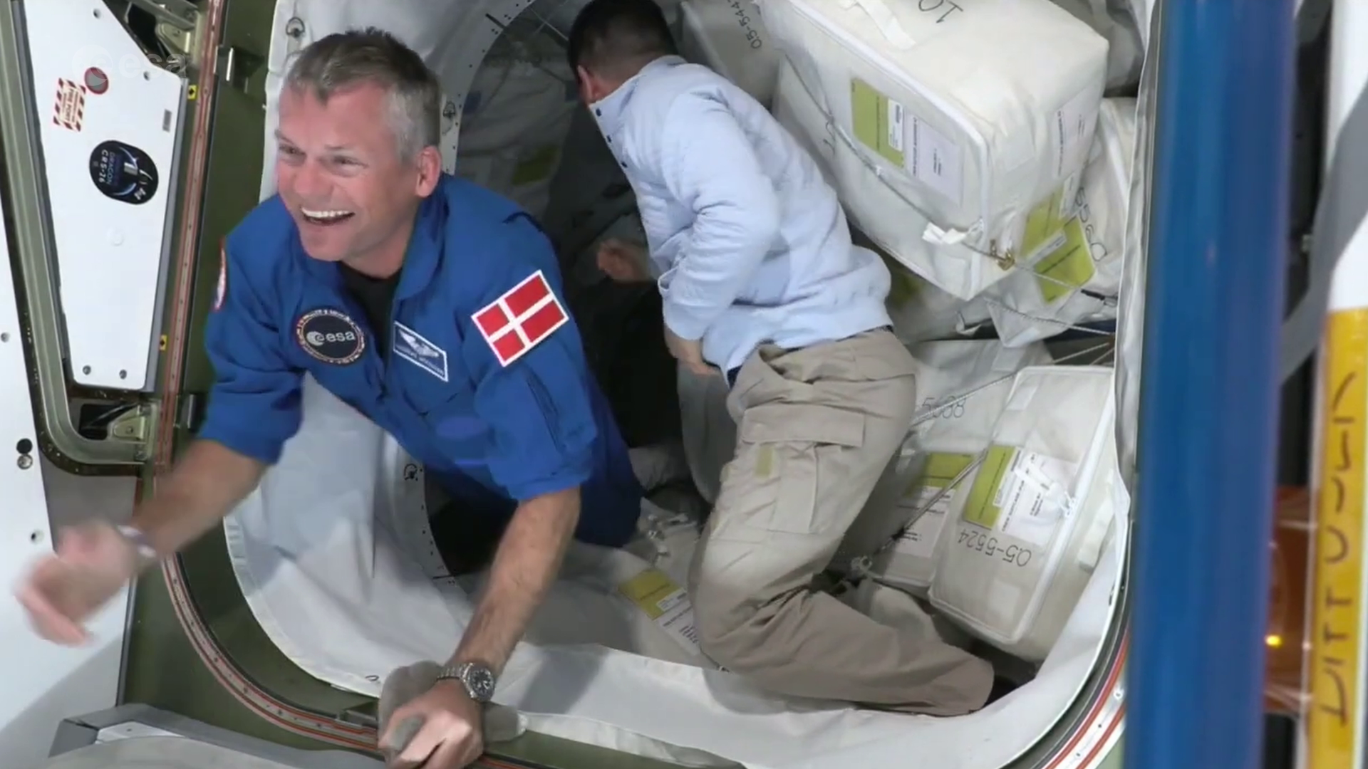 Smilende mann, vektløs i blå astronautdress med dansk flagg